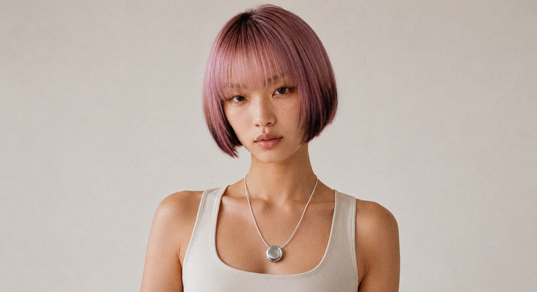 A woman with pink hair wearing the Pebb pendant on a silver cord