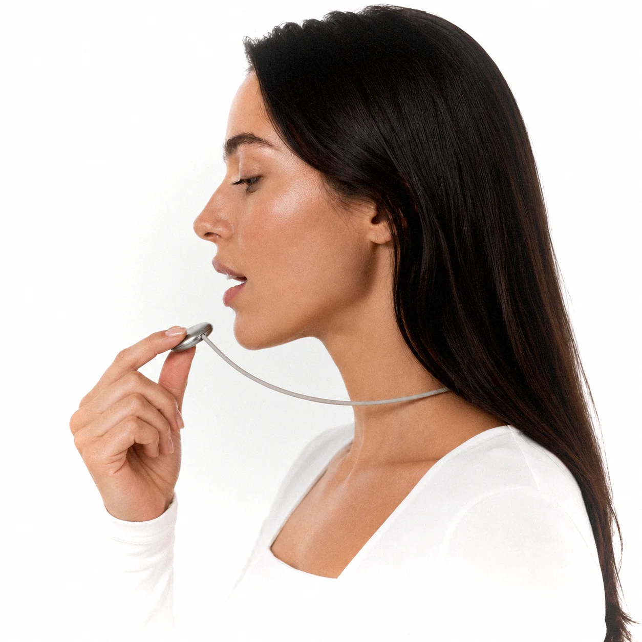 A woman in profile speaking into the Pebb pendant held near her lips