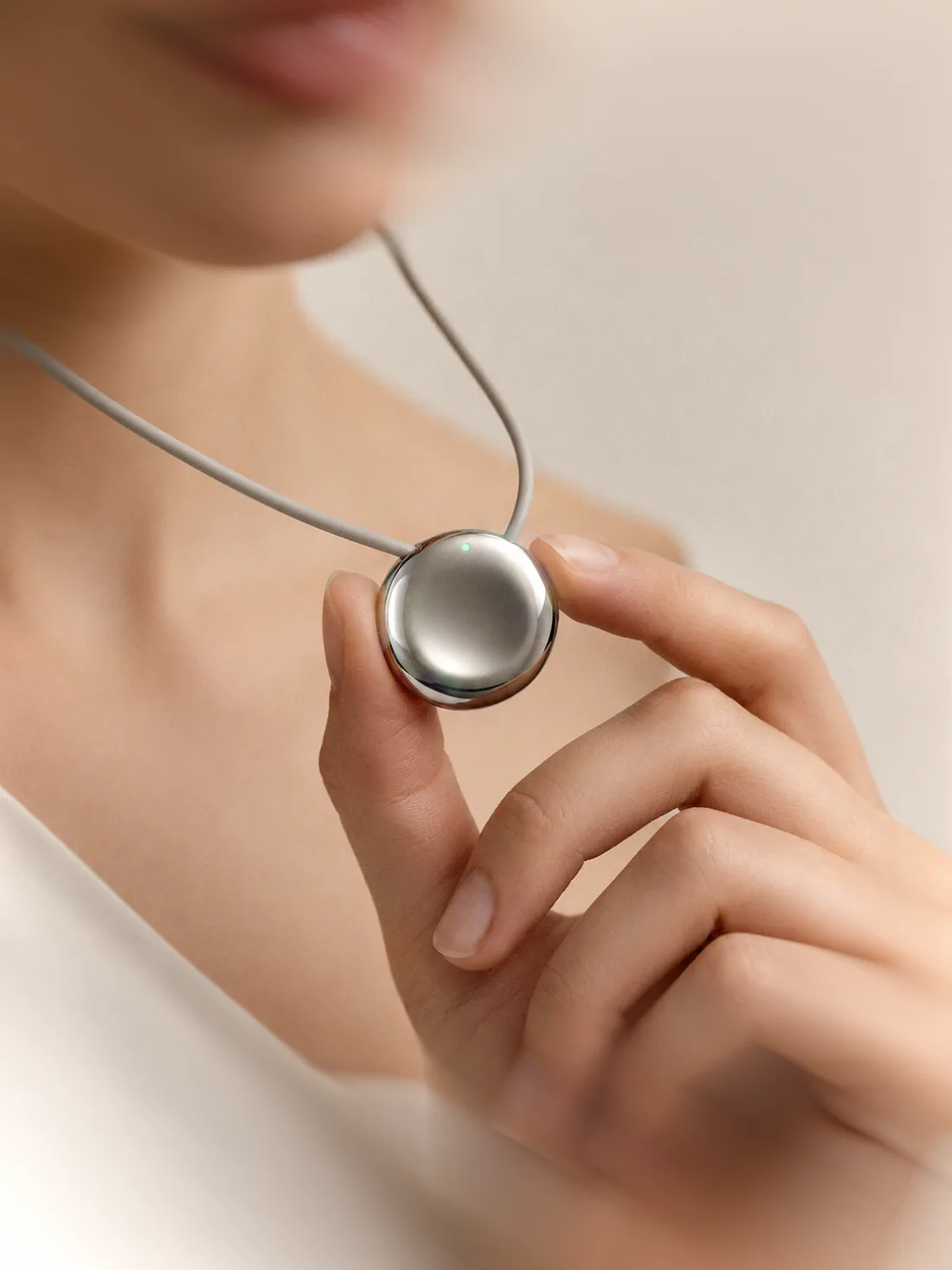A woman holding the Pebb pendant between her fingers